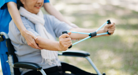 Asian physiotherapist helping elderly woman patient stretching arm during exercise correct with dumbbell in hand during training hand with patient Back problems in the garden.