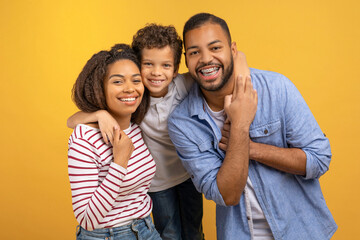 Obraz premium Happy African American family of three with preteen son embracing each other