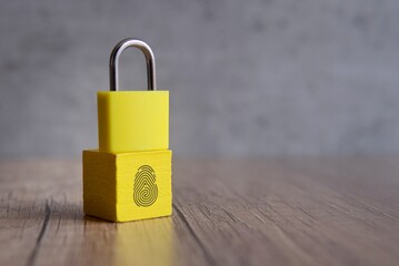 Padlock and wooden cube with fingerprint icon. Copy space for text. Biometric security concept.
