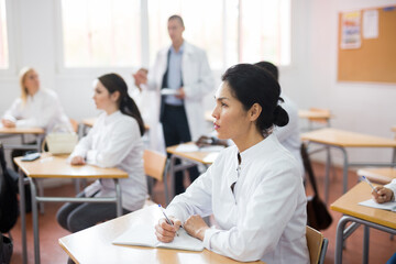 Portrait of confident asian female doctor listening lectures within refresher course. Professional development concept