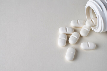 White pills scattered on a white background