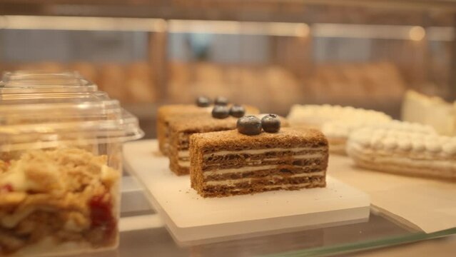 No people panning shot of delicious sweet eclairs, cakes and trifles on display in cozy bakery for sale