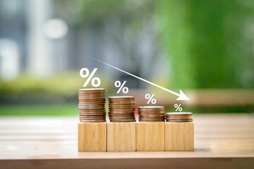 Low interest rates. Percentage sign on different high of coins stack and arrow going down. Business and financial banking, reducing interest rates payment, mortgage rate, loan and tax concept. - obrazy, fototapety, plakaty