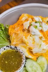 Omelet, fried beaten eggs on a white plate. Placed on a wooden table ready to eat.