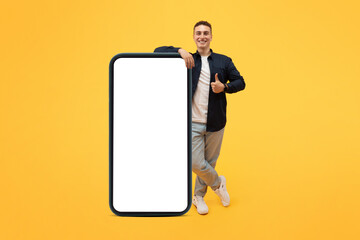 Positive stylish guy posing with big smartphone with empty screen