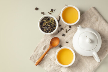 Obraz na płótnie Canvas Tea set on linen cloth, tea cups with dried tea leave and teapot on green background