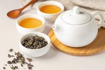 Tea set with dried tea leave, cups and teapot on table