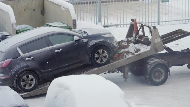Loading broken car on a tow truck in winter. Evacuation of a broken car in cold winter.