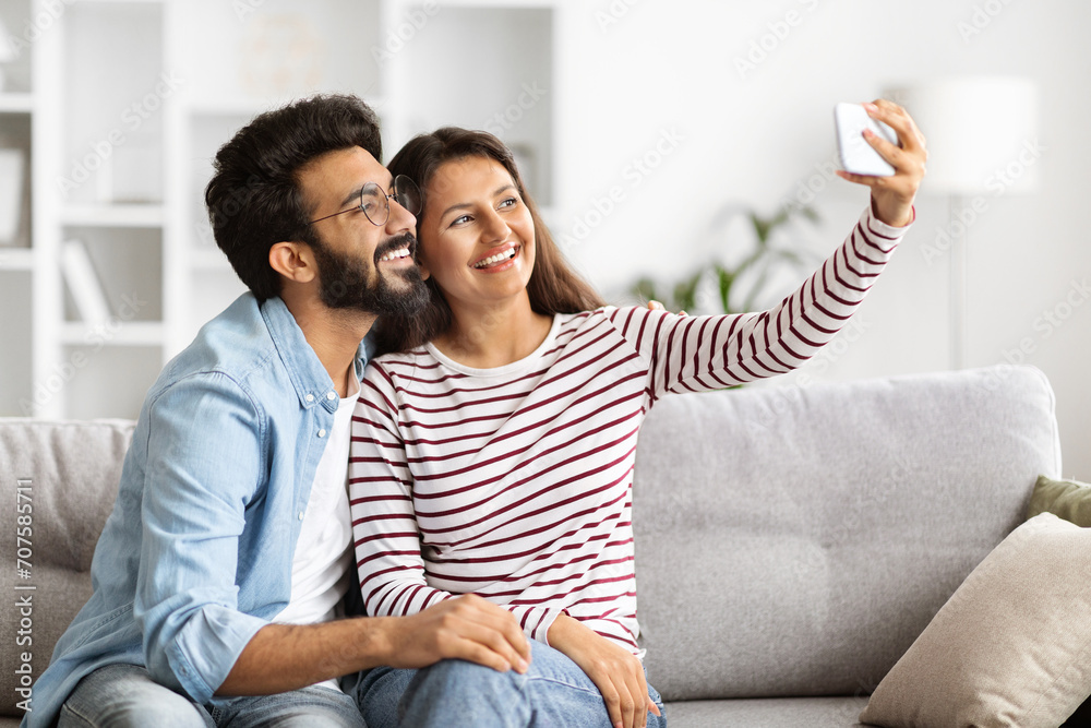 Poster indian man and woman taking selfie on smartphone at home