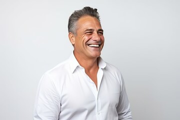 Portrait of a happy senior man smiling against a grey background.