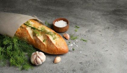 Tasty baguette with garlic and dill served on grey textured table, top view. Space for text