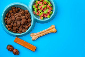 Dogs food in bowl and snacks on blue background