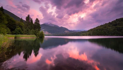Foto op Canvas  Beautiful pink cloudy sunset over a still mountain lake, dramatic colors photograph © Bounpaseuth