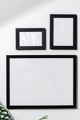Three blank frames with copy space hanging on white wall