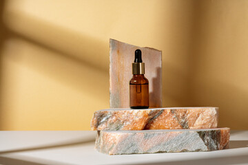 Cosmetic serum in an amber glass bottle with dropper lid with granite stone for composition