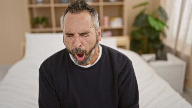 A mature bearded man with closed eyes and grey hair in a bedroom setting showing a range of expressions from calm to yawning.