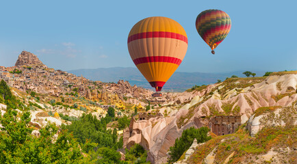 Hot air balloon flying over spectacular Cappadocia, Uchisar castle in the background - Goreme,...