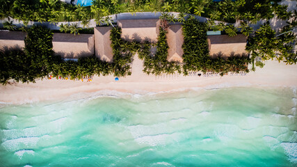 Fototapeta na wymiar Aerial view of a tropical beach resort with palm trees, thatched roofs, and turquoise waters, epitomizing an idyllic vacation destination