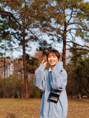 Beautiful young Chinese woman posing on green grass field in sunny summer day, wearing blue loose oversized top, mini skirt and white shoes. Emotions, people, beauty, youth and lifestyle portrait.