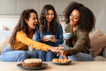 Three joyful multiethnic friends ladies share laughter over coffee indoors - obrazy, fototapety, plakaty