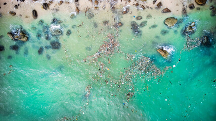 Aerial view of a polluted beach with plastic waste cluttering the pristine turquoise waters,...