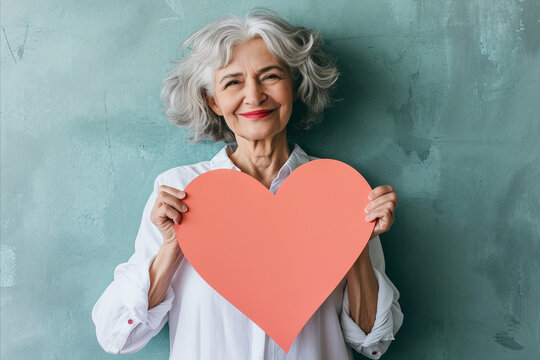 elderly woman holding a paper heart
