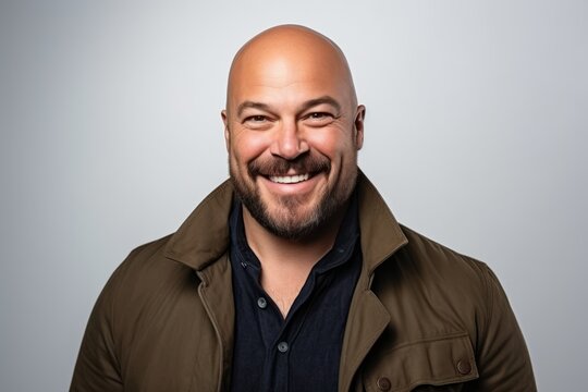 Portrait of a happy mature bald man smiling over grey background.