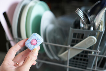 Woman holding dishwasher detergent in dishwasher machine, closeup