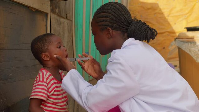 professional black female woman African doctor giving medicine to young kid children in africa small remote rural village medical healthcare prevention