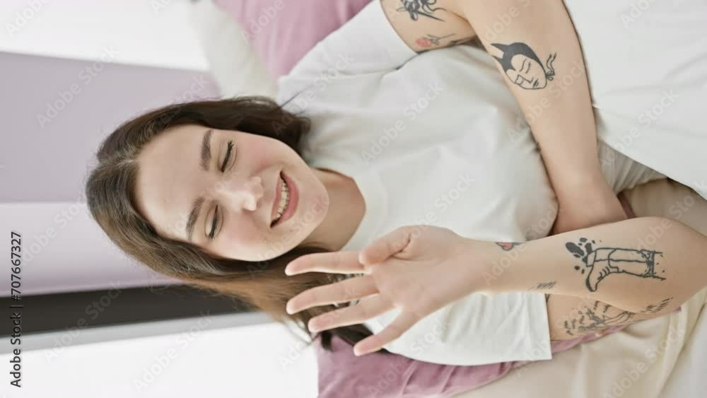 Sticker Cheerful young woman in pyjamas, radiantly counting four with raised hand, happily pointing up in cosy bedroom