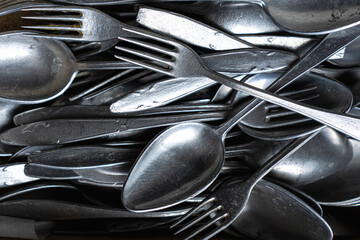 Pile of old worn vintage cutlery. Background of aluminium forks and spoons. Top view
