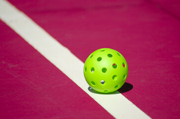 green pickleball ball isolated on a pink court
