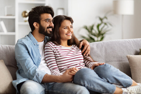 Sweet loving indian couple sitting on couch at home