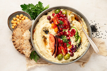 Hummus. Large bowl of homemade hummus garnished with chickpeas, vegetables and olive oil. Middle...