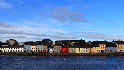 Vibrant array of houses in various bold colors, dotting the shoreline in Galway Ireland.