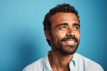 Closeup portrait of a handsome man with beard and mustache smiling at the camera over blue background