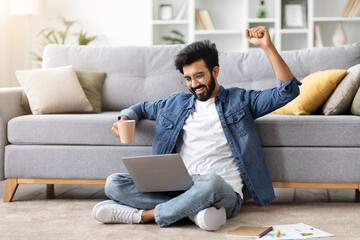 Ecstatic indian man with laptop celebrating victory or good news