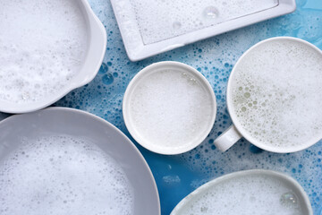 Plates, bowls and cups in foam of dishwashing liquid