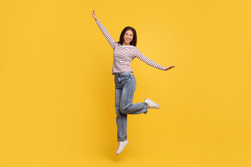 Cheerful carefree young asian woman dancing on yellow