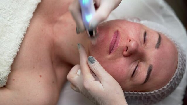 The cosmetologist conducts hydrafacial procedure to optimal condition of face skin. Lady at the next session of the cosmetology procedure in beauty salon.