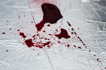 Red blood splatter on silver steel surface, soft focus close up, abstract backdrop