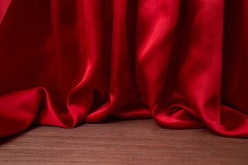 empty wooden floor with Elegant wavy red satin cloth curtains, defocused in the background, product...