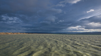 Surm am Bodensee, Wellen im Wasser, düstere Wolken. Sonne scheint wolkenlücke. Naturschutzgebiet im Hintergrund