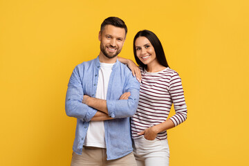 Portrait of happy young european couple posing over yellow studio background