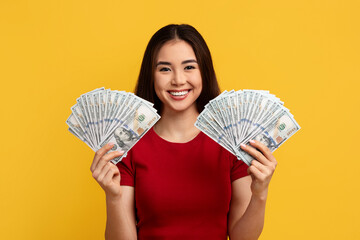 Happy rich young asian woman holding cash dollars