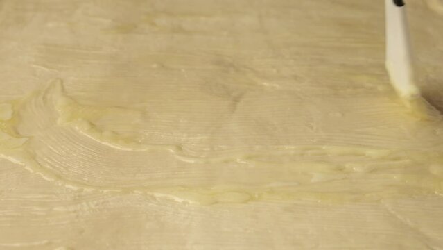 Greasing rolled out dough with an egg yolk liquid using a pastry brush before baking