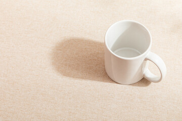 White mug isolated on Fabric background. Fabric surface. Drinking water. White mug. Beverage. Fabric surface. Simplicity. Minimalist object. Space for text. Mockup. Empty space.