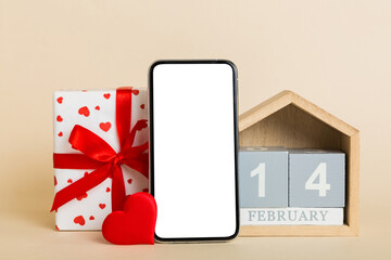 mobile phone with blank screen on colored background with hearts, calendar and gift box, valentine day 14 february concept perspertive view flat lay