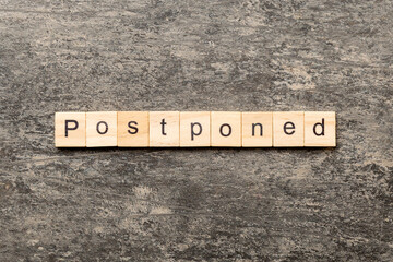 Postponed word written on wood block. Postponed text on cement table for your desing, concept