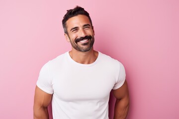 Portrait of a handsome young man in white t-shirt smiling against pink background
